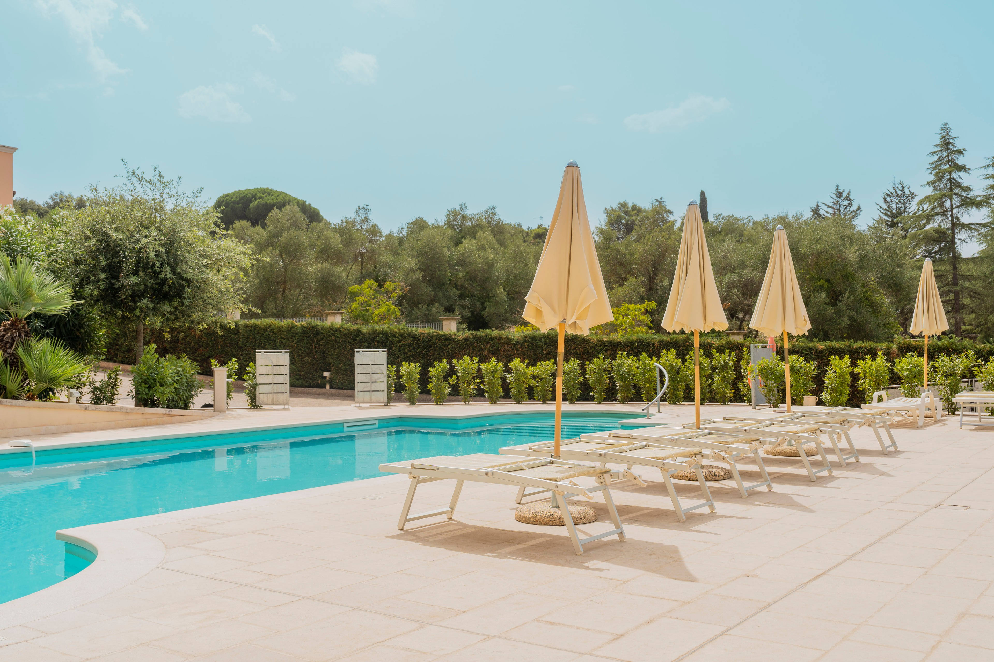 Piscina con lettini e ombrelloni tra il verde